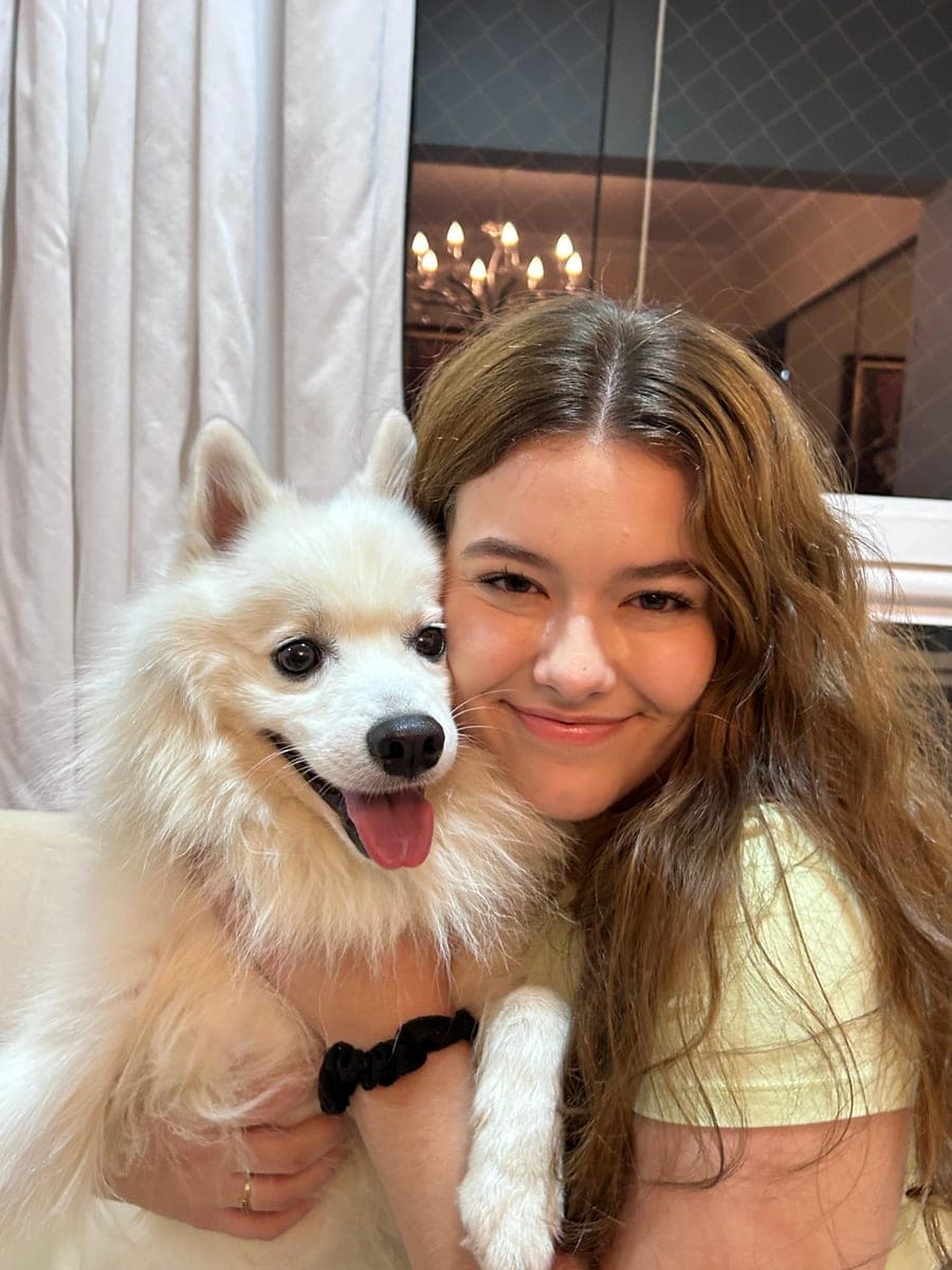 Sarah, a adestradora, abraçando um lulu da pomerânia branco